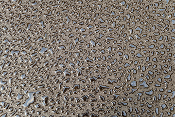 Water drops on a smooth gray surface. Abstract background. Fresh drops of various shapes on dark asphalt.