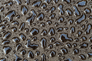Water drops on a smooth gray surface close-up. Abstract background. Fresh drops of on a dark asphalt.
