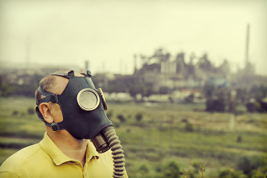 Man wearing gas mask on industrial factory background.