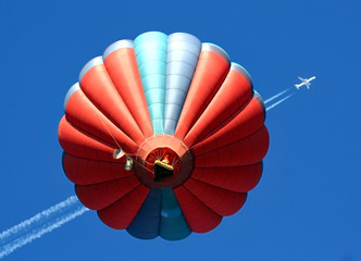 Hot air balloon passes below a modern jet aircraft