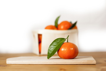 Mandarin orange fruits on wooden board on counter with leafs for healthy nutrition with vitamin c