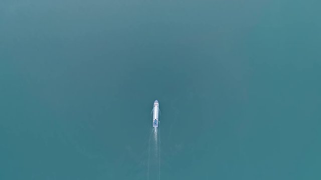 Aerial top view of pleasure boat sails on the lake on sunset