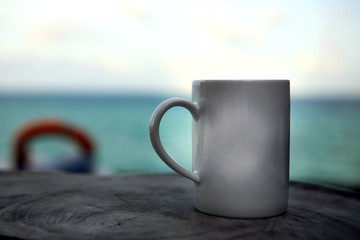 Blank white mug cup with ocean background, mock up image, right shifted