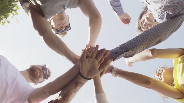 Group of young people putting hands together in circle.