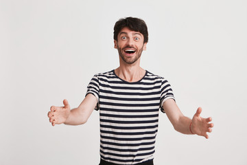 Portrait of cheerful amazed young man with bristle wears striped t shirt and opened mouth feels...