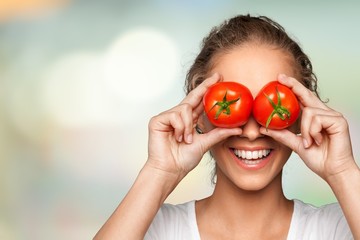 Beautiful laughing woman holding two ripe tomatoes - obrazy, fototapety, plakaty