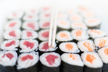 Rows of sushi rolls with chopsticks on top