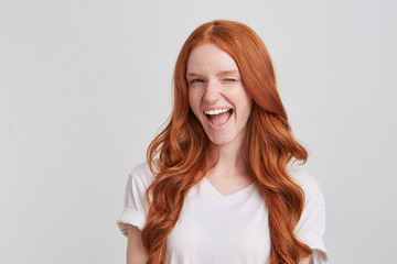 Closeup of cheeful playful redhead young woman with long wavy hair wears t shirt feels happy and...