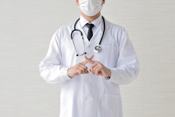 バツ印をつくる医師