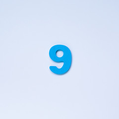 Wooden number 9 with blue color on white background.