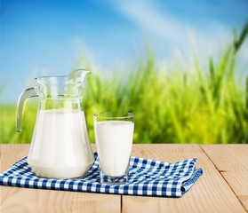 Glass of milk and jug on blurred