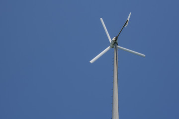 A wind turbin against a blue sky.
