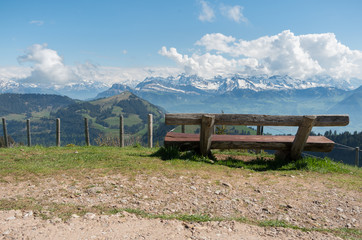 Brown wooden chair overlooking the swiss alps on mount rigi. Rest station with a view. Snow capped...