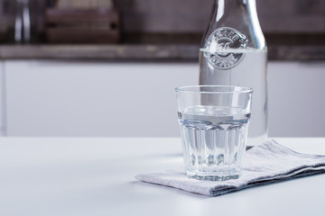 Glass of pure water and bottle on kitchen table. Clean Concept
