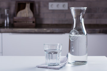 Glass of pure water and bottle on kitchen table. Clean Concept