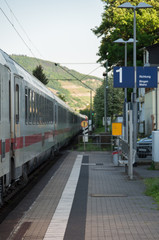 Obraz premium White train passing through station with focus on platform number