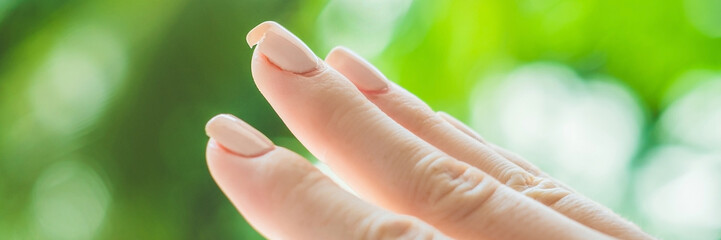 Broken nail on a woman's hand with a manicure on a green background BANNER, long format