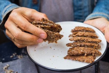 Woman hands holds dark rye bread slices. Homemade dark bread with coriander seeds on plate. Vegan vegetarian healthy food. Bread made of whole grains on dry frying pan. 