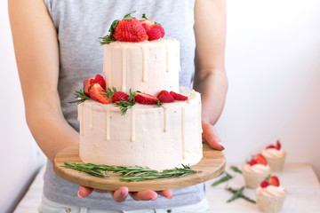 Cake in female hands. Big cake with strawberries and raspberries. Cake for wedding, birthday.