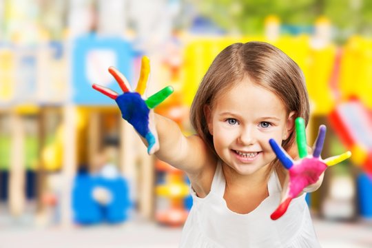 Little girl showing painted hands on background