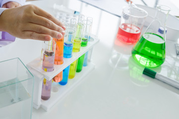 Scientist female hand with white desktop and colorful test tube, Beaker. Copy Space image.Concept Science and Medical image.