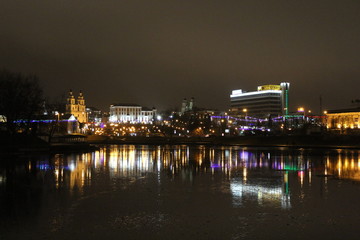 view of the night city lit by lights on the other side of the river