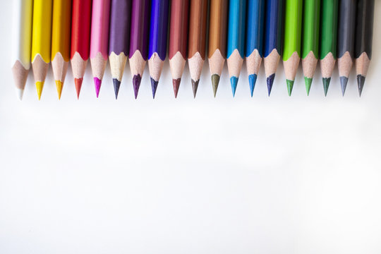 Colorful crayons on a white background. All the colors on the crayons. White, yellow, orange, pink, purple, blue, green, black crayon. Back to school. Starting a new school year