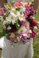 Bride in Lace Wedding Dress Holding a Vibrant Bouquet - Pink, White, Green, Purple, and Fuchsia Floral Arrangement with Anemones and Dahlias in the Hands of a Young Bride