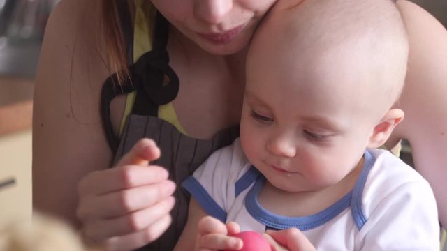 A little baby with her mother decorating Easter eggs, slowmotion