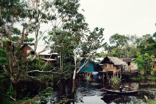 stilt houses on the amazonas river in Colombia with a man on a dugout canoe