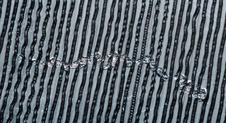 Extreme close up macro photo of the surface of a vintage vinyl record including grooves, dust and a typical surface scratch.