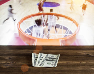 Money dollars on a wooden background on the background of a TV showing basketball