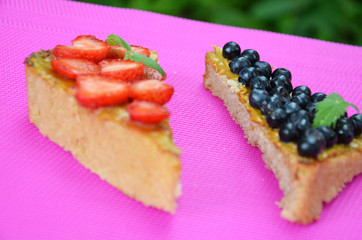 a sandwich with strawberry blueberries and peanut butter on a crimson background. top view of a sandwich on a background of green foliage in the garden. copy space. a healthy snack
