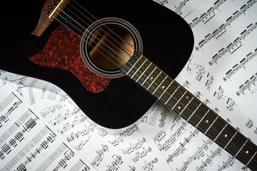 dark acoustic guitar on a background sheet notes, close-up