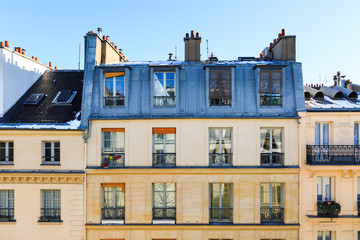 View to typical facade of parisian building. Traditional french old house with typical balconies, windows, rooftops and chimney pots. Cityscape from window of Paris, France.