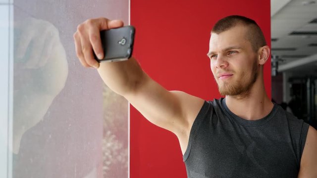 Young strong guy in gym doing selfie photo for social media instagram