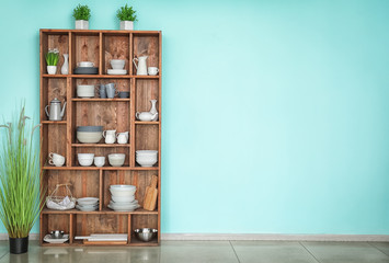 Kitchen shelving with dishes on color wall background - obrazy, fototapety, plakaty