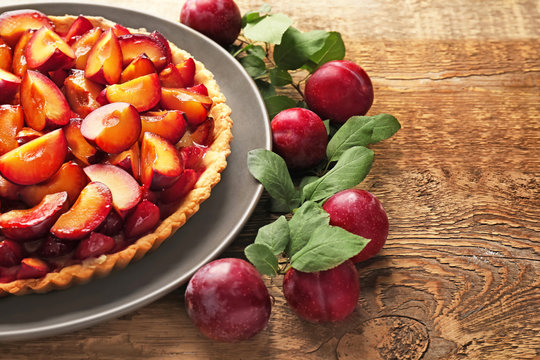 Delicious pie with plums on table