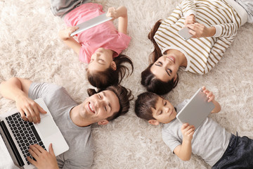 Young family with gadgets at home, top view