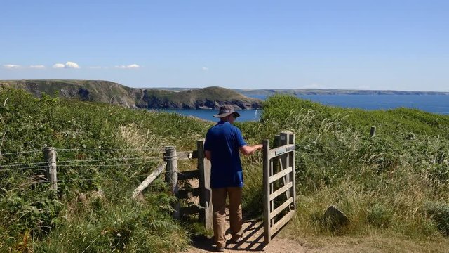 Man walking up to a gate on the coast path, Pembrokeshire