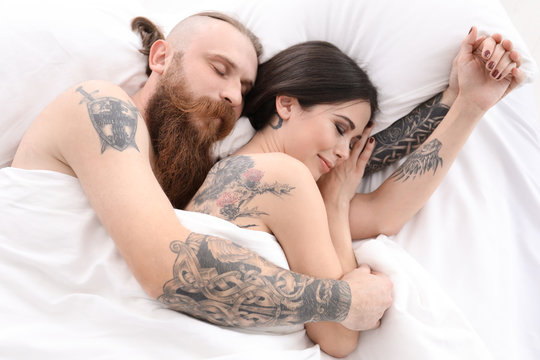 Attractive young couple with tattoos in bed
