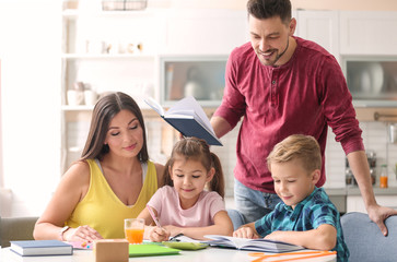 Brother and sister doing homework with parents