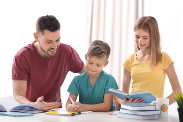 Brother and sister doing homework with father