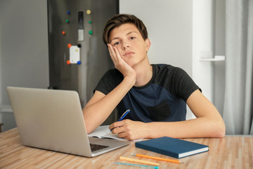 Tired teenager boy doing homework indoors