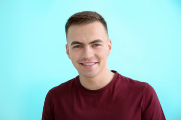Young man smiling on color background