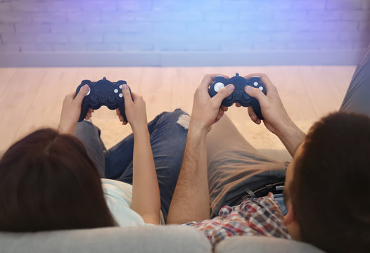 Young couple sitting on sofa and playing video game at home