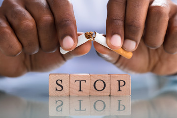Person's Hand Breaking Cigarette Over The Stop Blocks