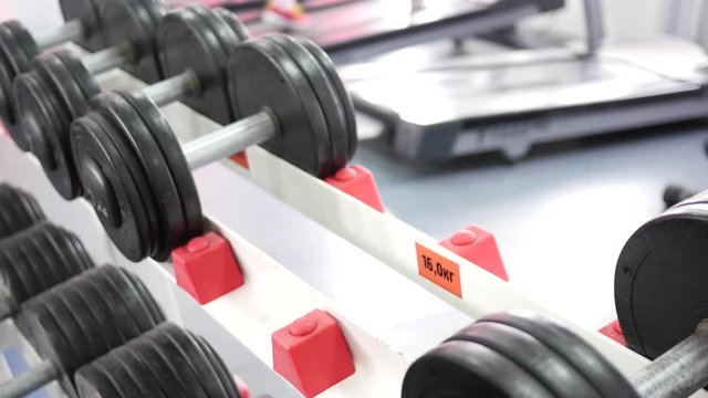 Sports man hands take dumbbells from gym stand and lay them back
