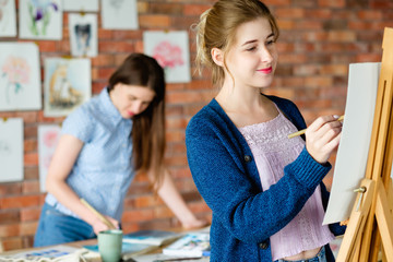 art painting hobby. creative leisure. girl drawing a picture on easel in a workshop. talent inspiration creation and self expression concept.