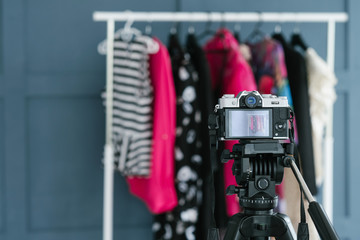 fashion blogging and video streaming. style beauty and trends in social media concept. camera on tripod focusing on clothes on the rack.